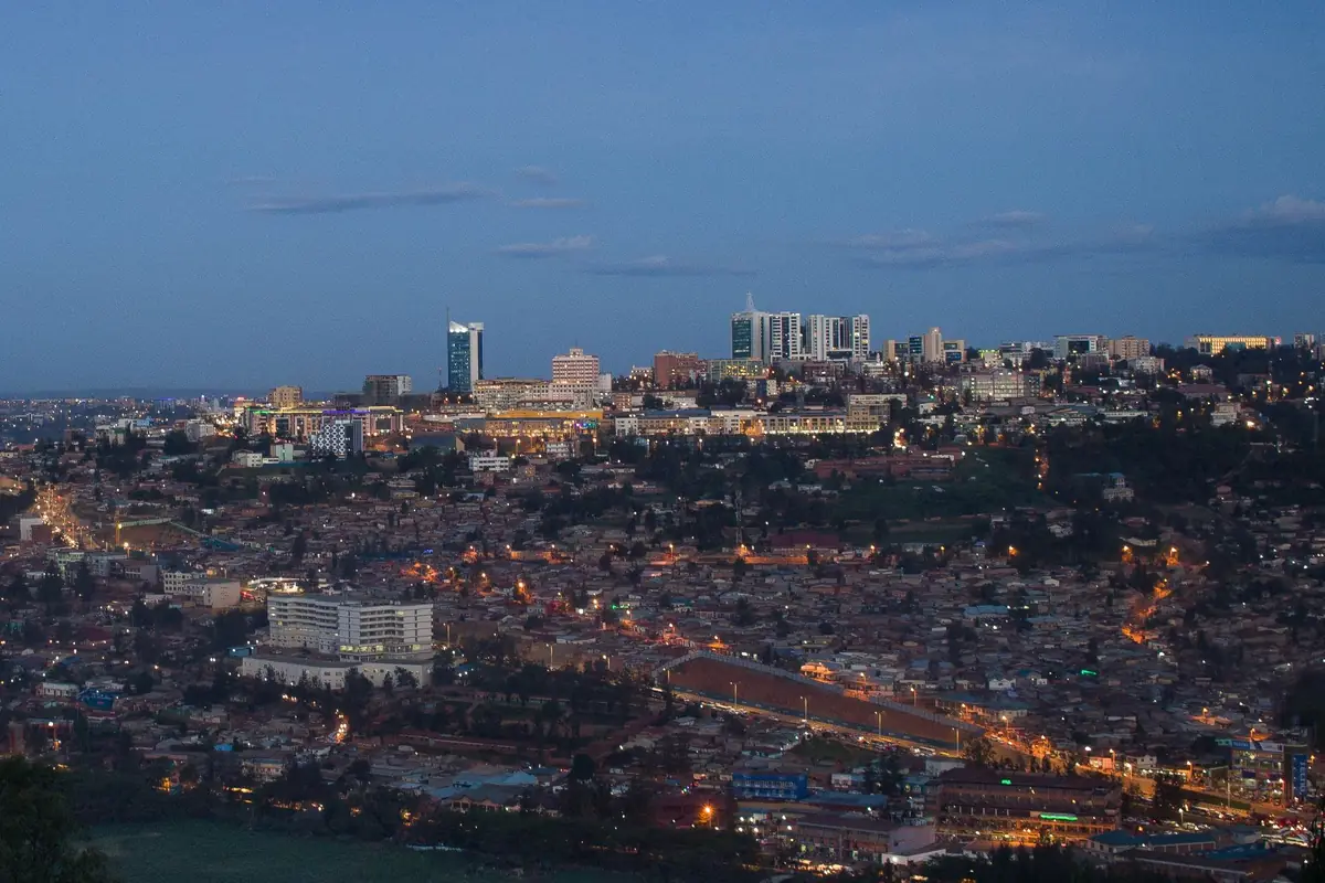 Kigali's hillside city centre at dusk, with office towers lit against a deep blue sky